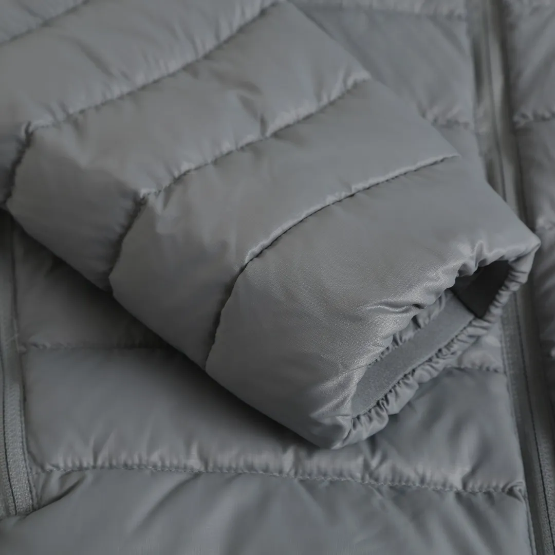 BP Can Goos Quilted Badge Down Jacket Fabric Selection: Made of nylon fiber through high-density lattice tear-proof weaving process, the surface forms a fine checkered texture, and the warp and weft yarns are interlaced to strengthen the structural toughness of the fabric, effectively blocking external pull, and making it less prone to snagging, tearing and damage. After dense post-finishing treatment, the fabric surface is light and compact, with a soft matte texture. It also has windproof properties and can block the penetration of cold wind. The texture of the fabric is light and soft, without any heavy or stiff feeling, and the upper body does not feel weighed down. It also has good anti-wrinkle properties. It is not easy to produce stubborn wrinkles after rubbing, and it is not easy to leave dead wrinkles after daily storage and folding. It is easy to care for, taking into account both lightness and durability. Quilting technology: Using horizontal segmented lock velvet quilting technology, the stitching is straight and regular, and the stitch spacing is even and fine. Divide the garment body into regular horizontal down filling compartments to effectively fix the down inside, prevent the down from clumping and shifting after wearing and washing, and allow the down to be evenly distributed in each cavity. The seams are made with tight workmanship, the pinholes are small, and the high-density fabrics greatly reduce the risk of velvet getting out. The overall quilting lines are simple and neat, creating a simple and smooth body shape, without being bloated and bloated, and the upper body is flat and straight. The sleeves and body are individually quilted, giving both freedom of movement and velvet locking capabilities. High-quality filling: 90% white duck down is selected as the filling material for the inner lining. It has a high velvet content, full and fluffy velvet, few impurities, and excellent temperature-locking and warmth-preserving properties. The whole piece is filled with about 170g of down. The amount of down is sufficient and the filling is full and even. It can lock the air to form a thermal insulation layer and effectively block the intrusion of cold air from the outside. Details: The inner cuffs are equipped with elastic bands to naturally form a micro-cinch effect. The cuffs are smooth and dense, the stitching at the fabric splicing is even, and the workmanship is meticulous. The elastic structure can fit the wrist tightly, effectively prevent cold wind from entering through the cuffs, and lock in the warmth inside. It has moderate stretch and elasticity, so it doesn't strangle your wrists when worn, and your arms can be raised and raised without being restricted. At the same time, it can prevent the cuffs from moving up during wearing, making it easy to put on and take off. The placket adopts hemming technology, and the hemming strip completely covers the raw edge of the placket piece, storing all the trimmed edges to prevent the edge yarn from being exposed. The width of the hemming is uniform, the wiring is consistent and smooth, and the corners are clean and neat, without wrinkles or bulging. Accessories: One-to-one customized embroidery stamp, One-to-one customized zipper puller, One-to-one customized three-label Size: S M L XL Style number: D